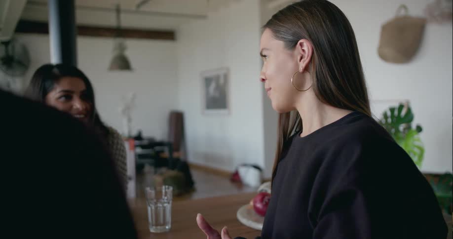 A group of people have a conversation at a kitchen table