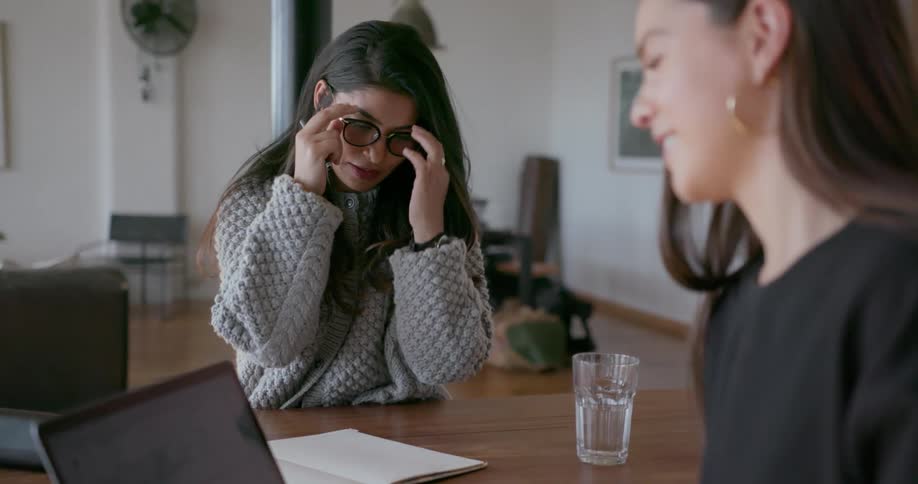Two woman are sitting at a table and having a conversation about work