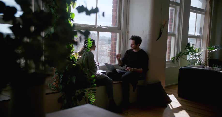 Man and woman sit in window seat talking