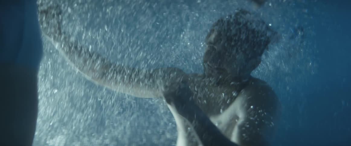 Woman playfully pushing man under water in a pool