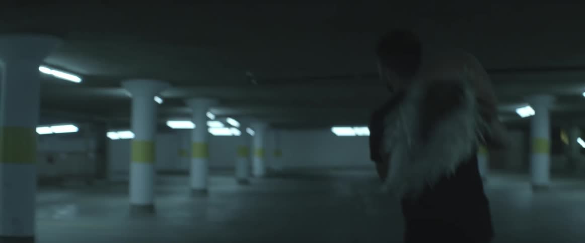 Man playfully picking up blonde woman and spinning her around in a parking garage