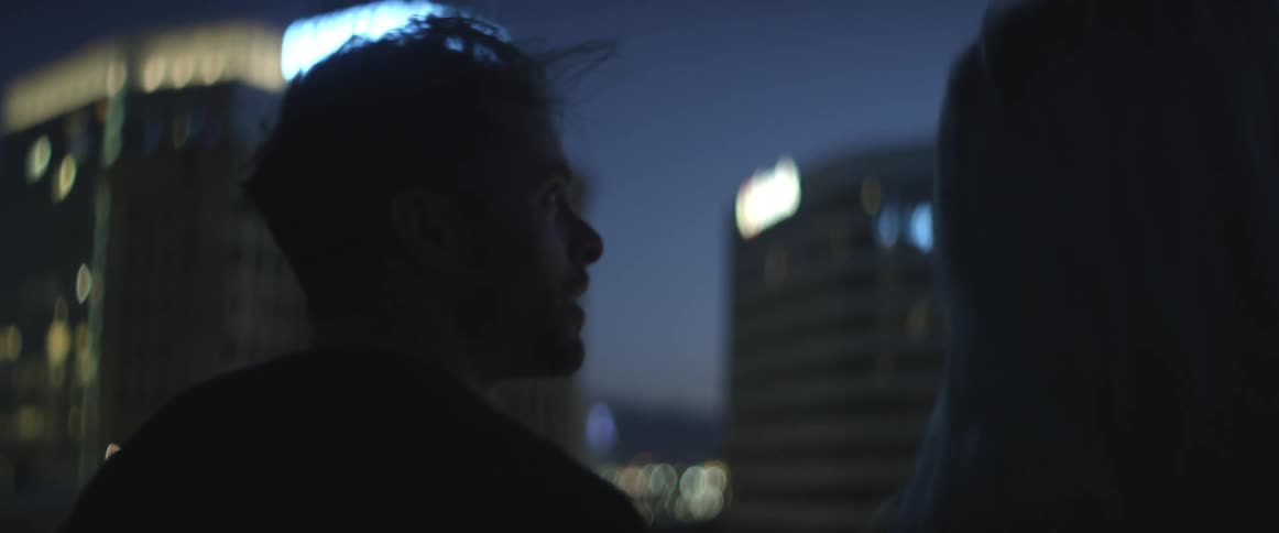 Couple outside looking up at the city skyline at night