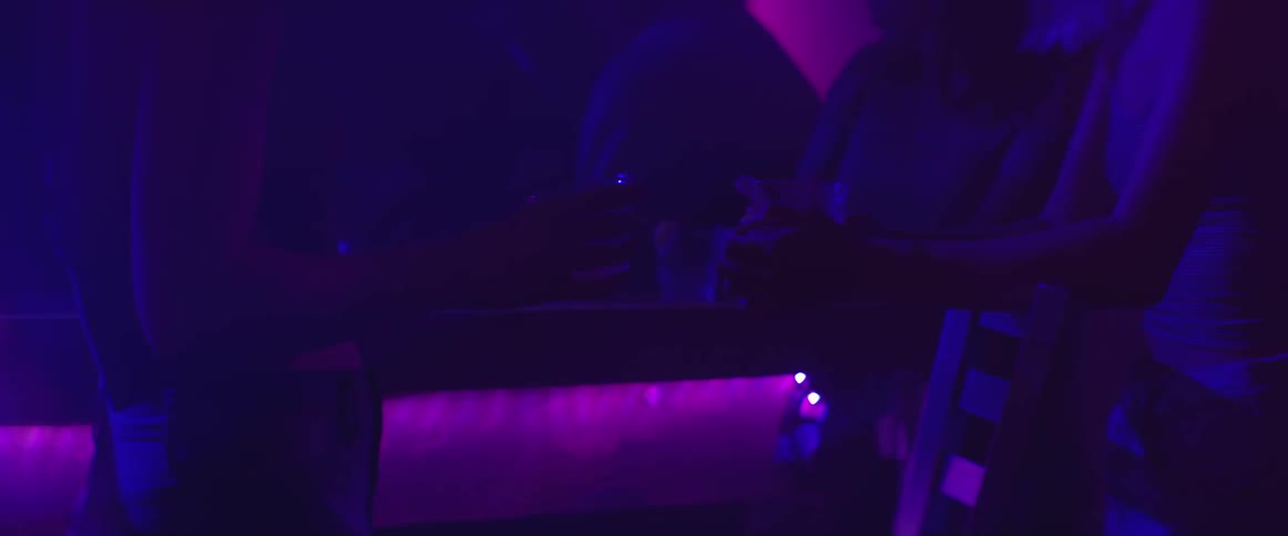 People holding their drinks in a dark club