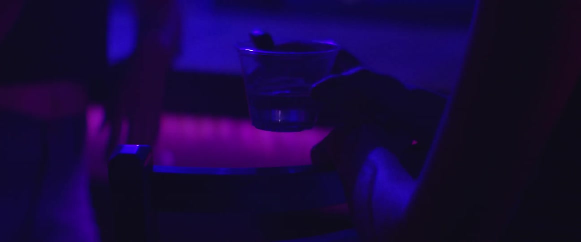 A person is holding a drink in a dark club