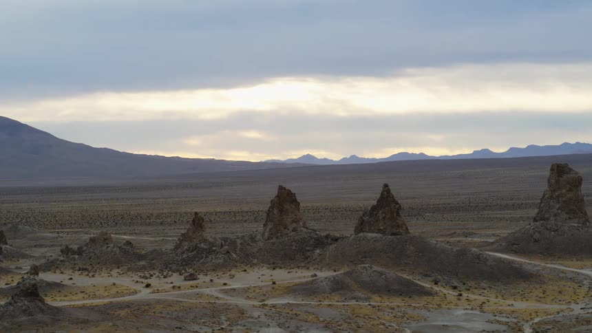 Aerial view of rock columns rising over the desert close to the mountains at evening