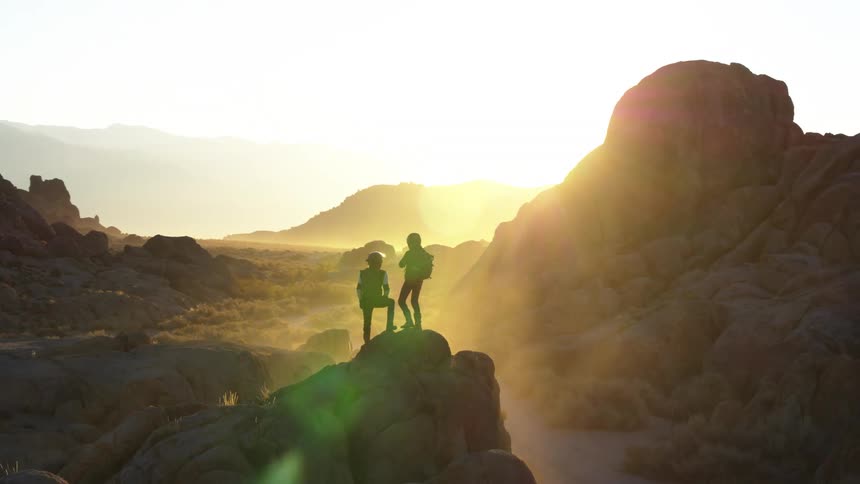 Two people are standing on the rocks watching the sunrise