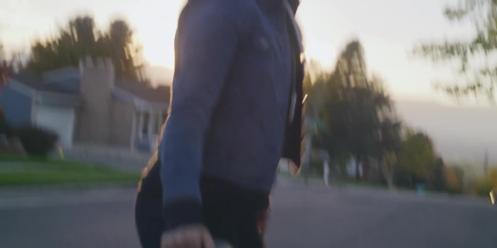 A woman runs down the middle of a neighborhood street carrying a helmet