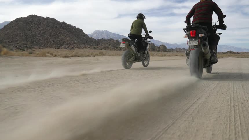 Two people riding dirt bikes outdoors
