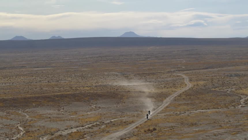 Two people race dirt bikes in the desert