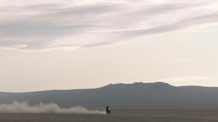 A person races a motorcycle across a soil field
