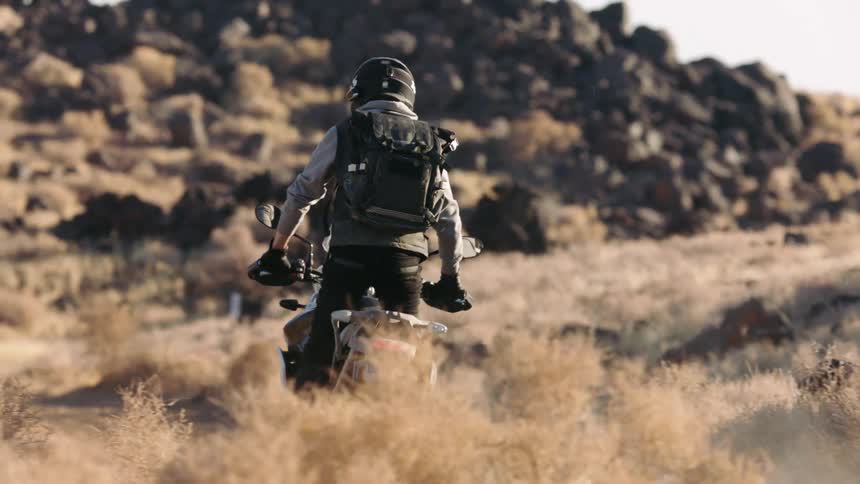 A person is driving a motorcycle through the wilderness