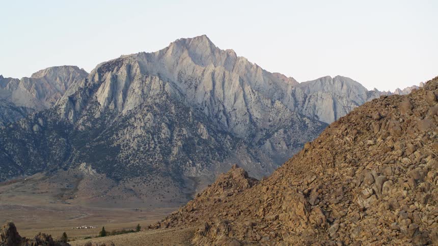 Village sits in valley between dirt mounds and vegetation covered mountains
