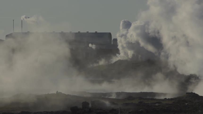 Smoke and vapor rise from factory as bird flies over plain