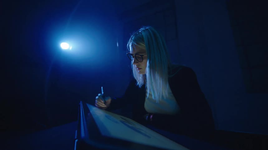 A woman is drawing on a tablet in a dark room