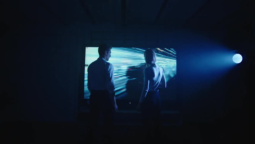 Man and woman are walking up to a television screen