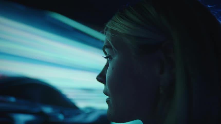 A woman is watching a television display in a dark room