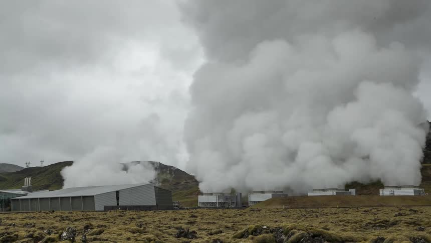 Smoke billows from sheds in a field near the hills and mountains