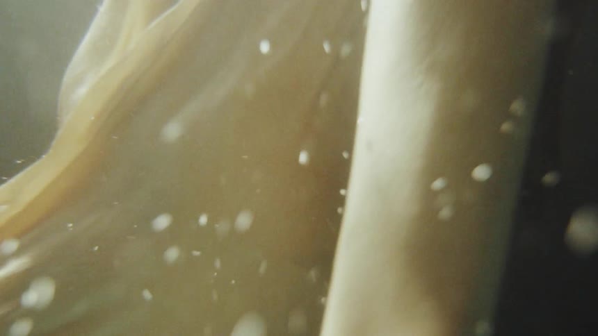Woman wearing a gown swims towards the surface of the water
