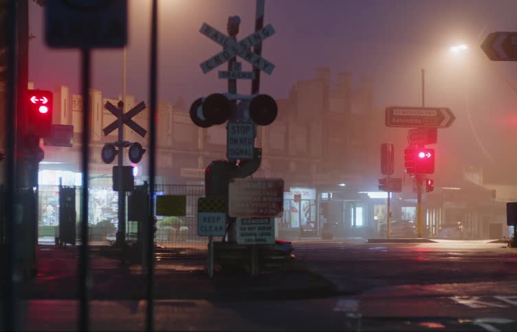 Railway crossing red lights and signs across from retail stores at night