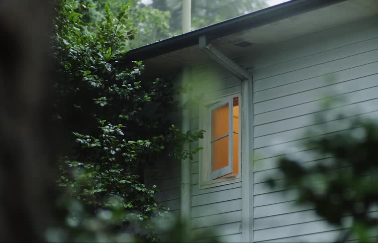 Light shines inside room with partly open window set next to gutter drain