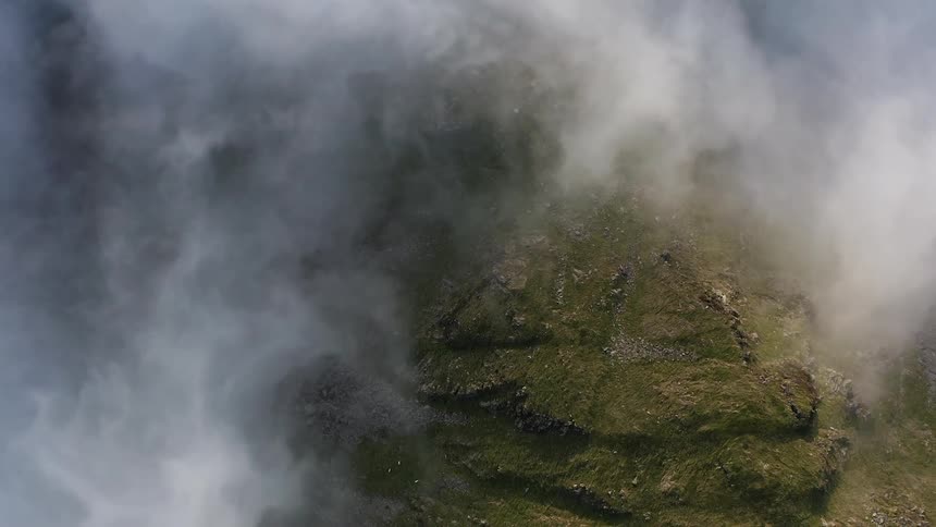 Clouds swirl around the mountain top