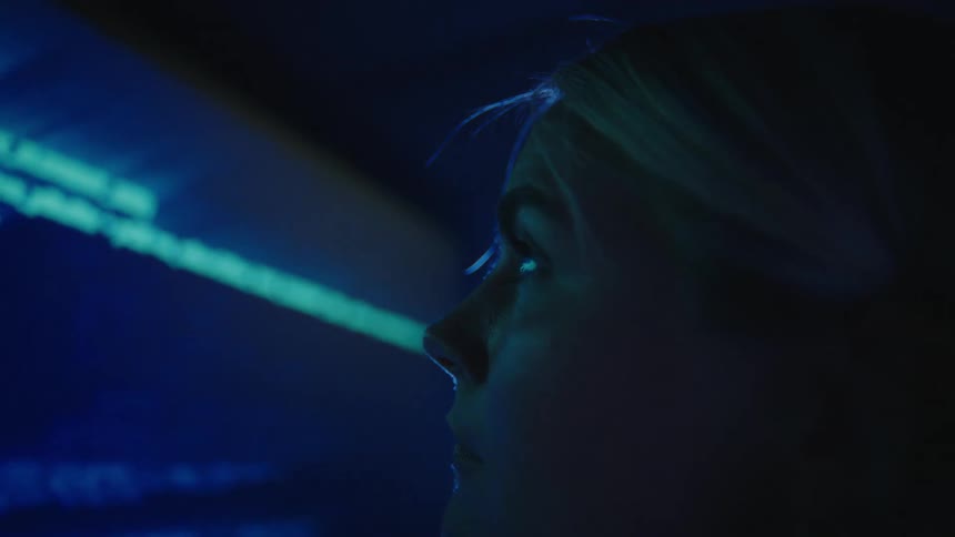 Woman looks at a large monitor with text scrolling on it