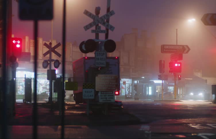 A delivery box truck drives over train tracks and waits at a traffic light