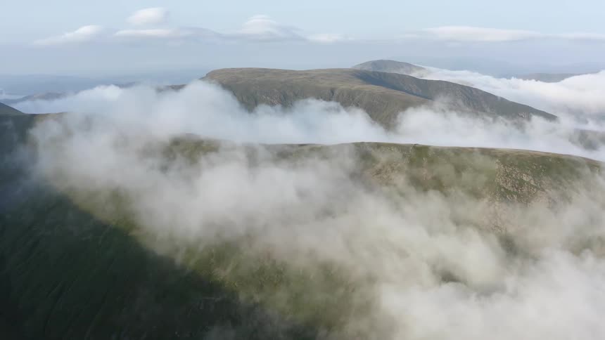 Heavy mist surrounds the mountains under a blue sky