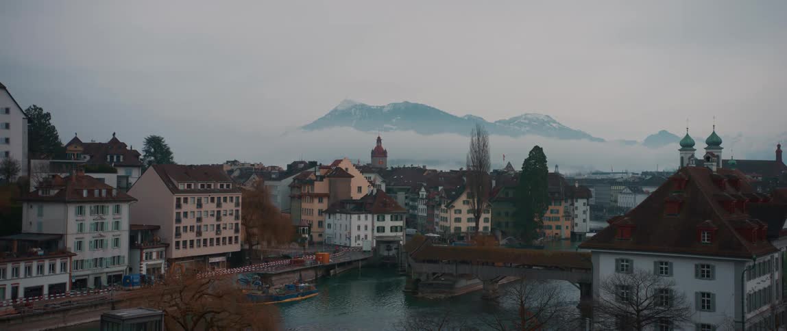 River stretches under a bridge near the towns buildings with mountains in the distance
