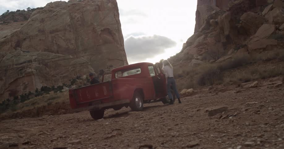 People get out of a red tow truck by a canyon