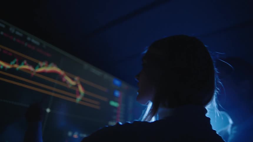 Two people look at a graph on the monitor