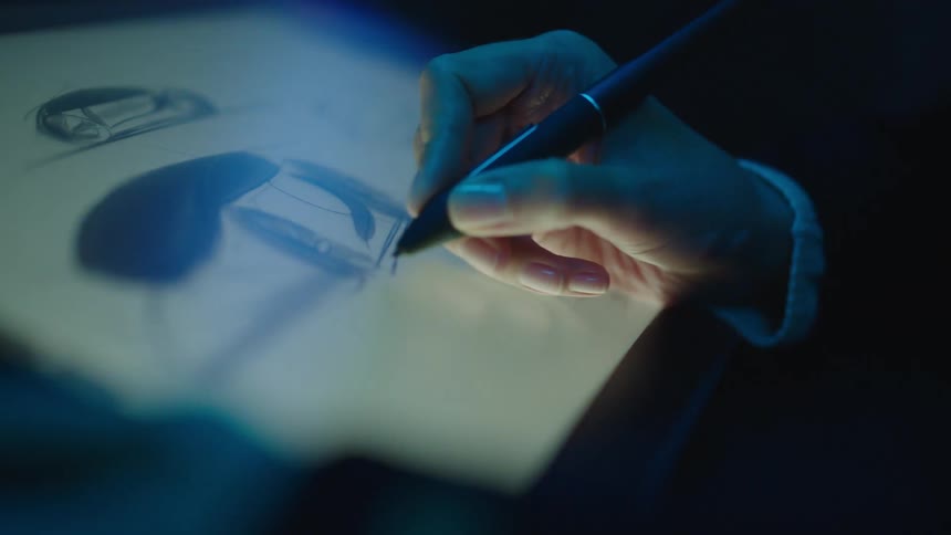 A woman uses a stylus pen to sketch on a tablet