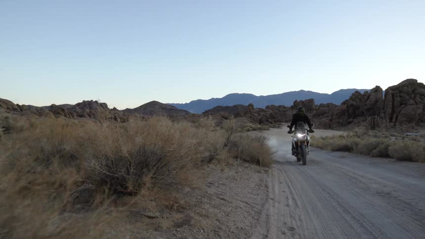 Two people are riding motorcycles through the wilderness