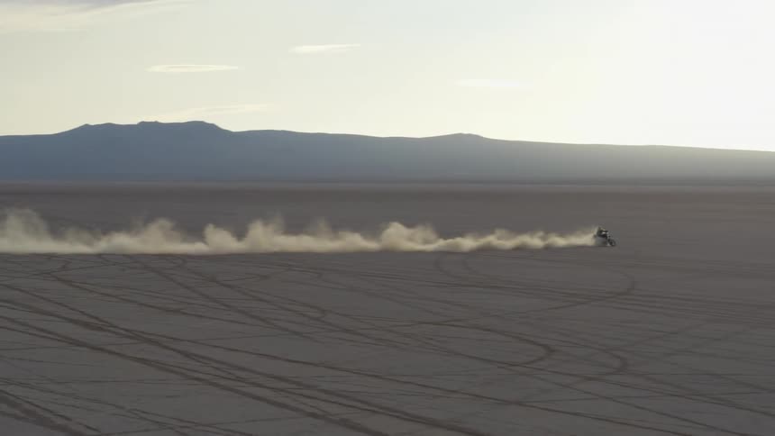 Aerial view of bikers riding and skidding in the desert at dusk
