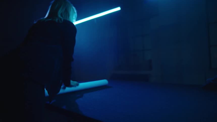 A woman in an office unrolls a blueprint on a table