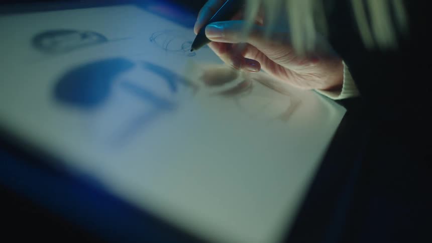 Blonde woman uses a stylus to draw concept art of vehicles on a touchscreen