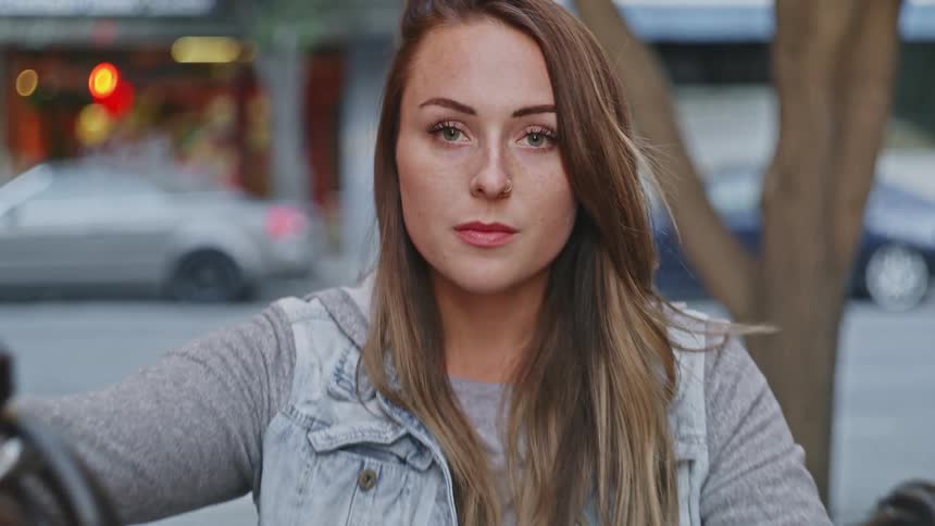 A woman is sitting on a motorcycle in a downtown city