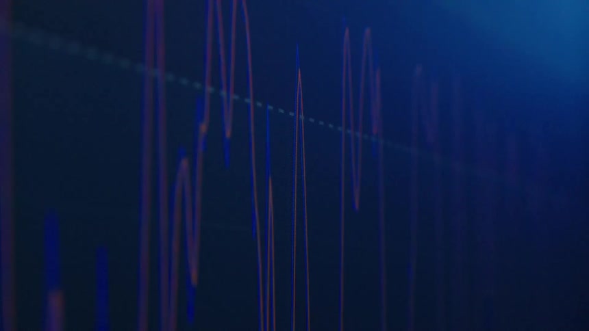 Close up of a line graph on a screen under a blue light while the camera comes on and off focus