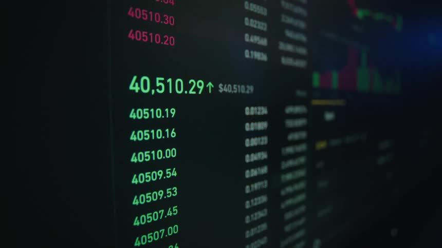 Close up of the changing numbers on the indicators of a trading website on a screen inside a dark room