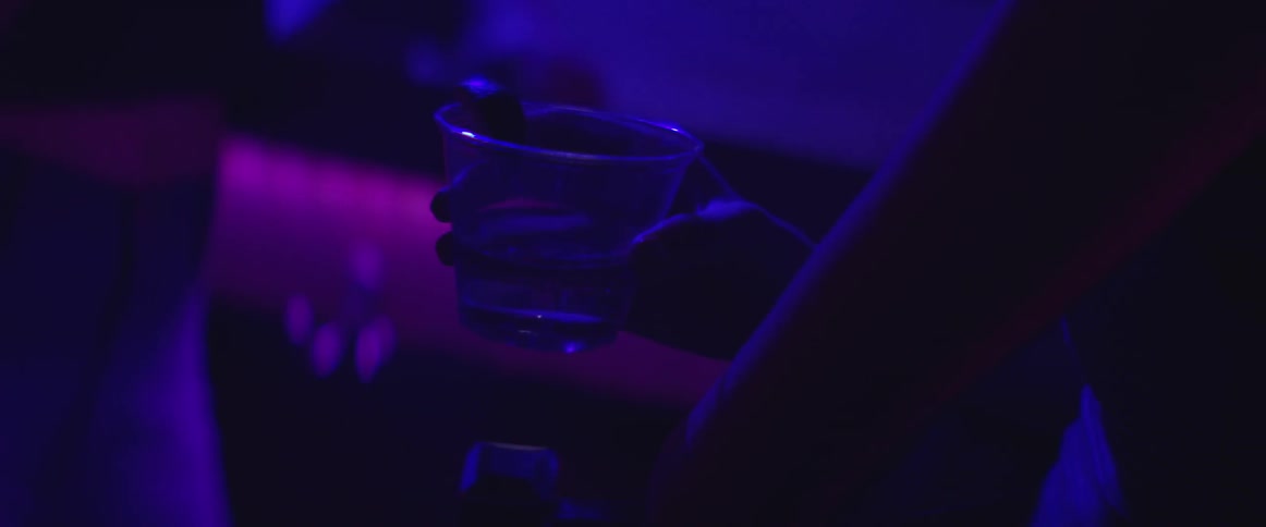 A person is holding a glass in a dark club