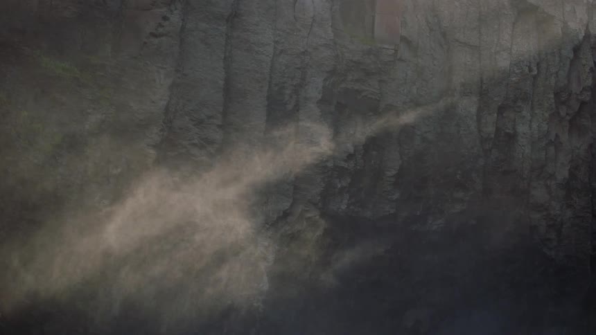 Sun shines through fog in front of cave