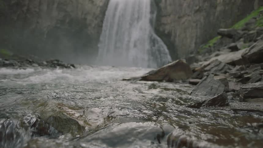 Waterfall cascades down cliff and water flows