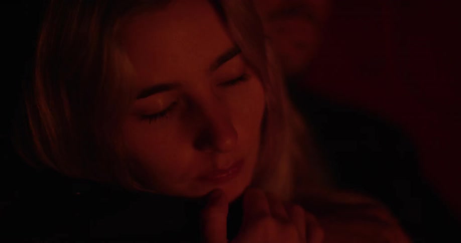 A woman blinks slowly in a dark area