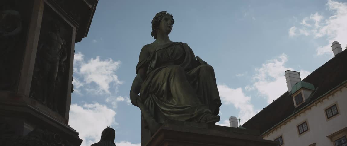 A sculpture of a woman near a pillar outdoors during the day