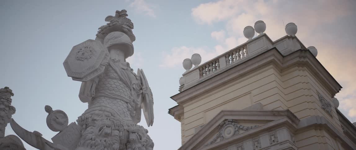 Statute sits near ornately detailed building under a cloudy sky