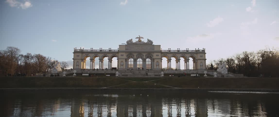 Tourists walk around and through the gloriette in the schonbrunn palace garden in vienna