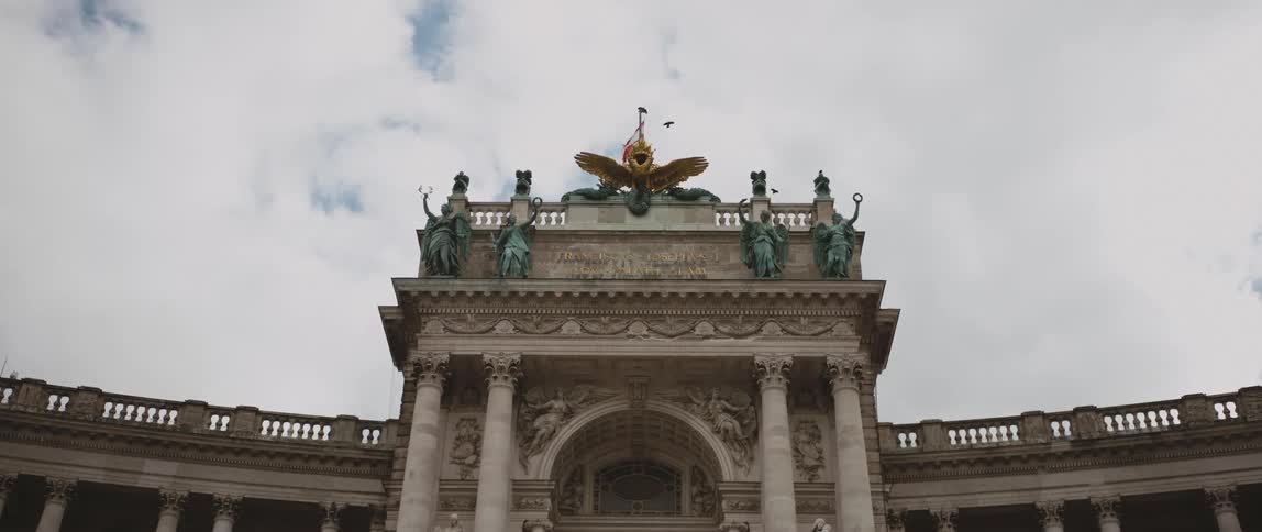 A flag blows in the wind above viennas imperial hofburg palace