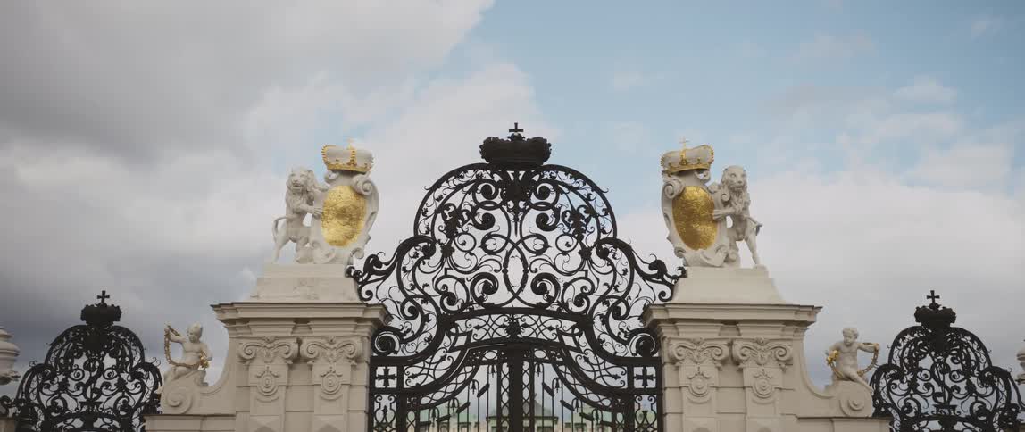 Statues flank the sides of an ornate wrought iron gate