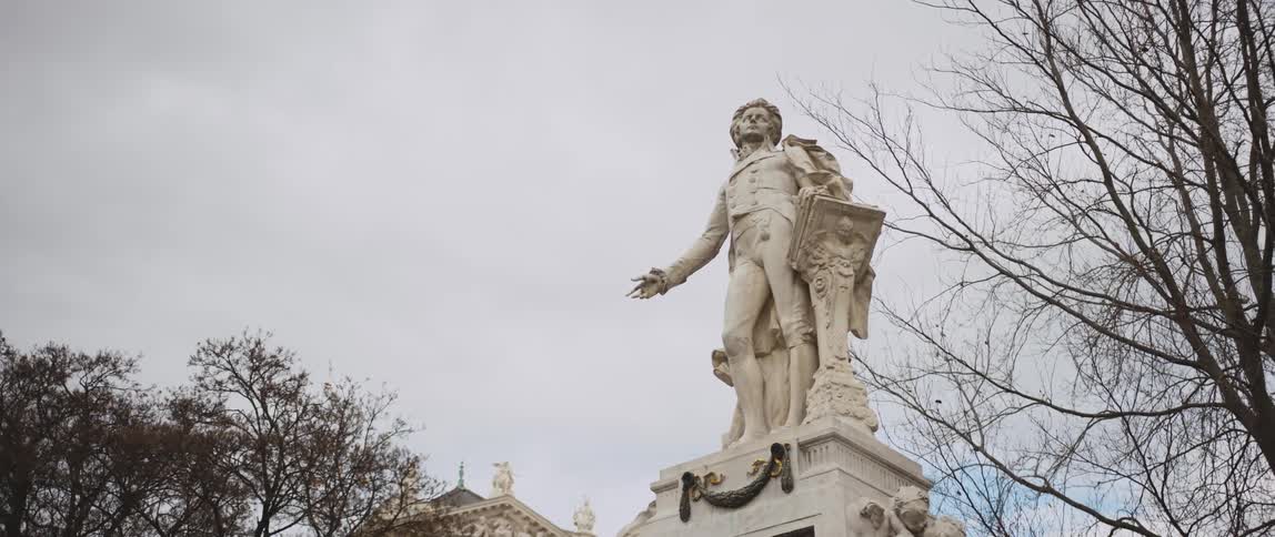 A historical sculpture of a man sits on a pedestal