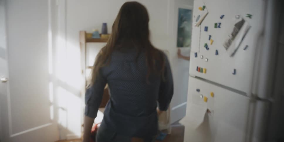 A woman runs through a house angrily and slams a door
